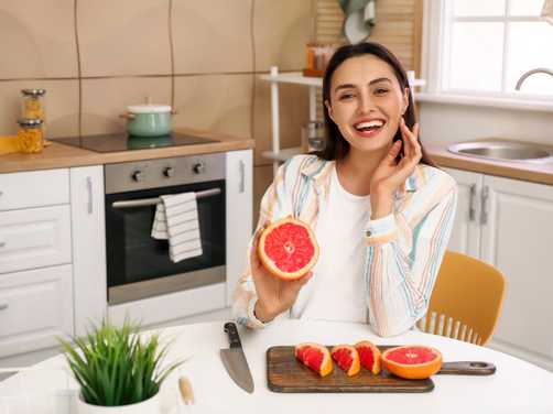A smiling woman holding a grapefruit